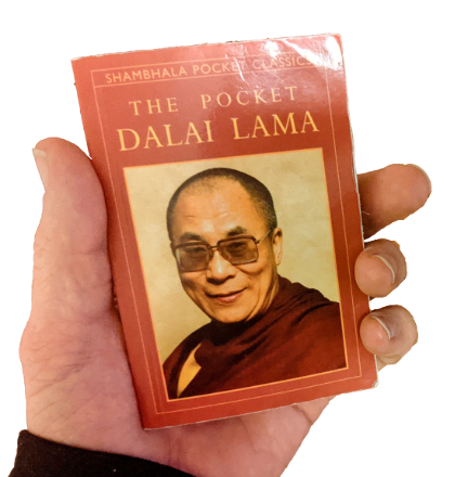 A hand holding a small paperback pocket edition book.