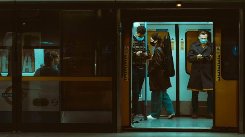 Three commuters on a train, all checking their phones instead of each other.